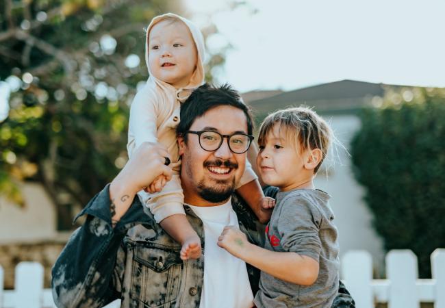 Parent supporting two kids in their arms.