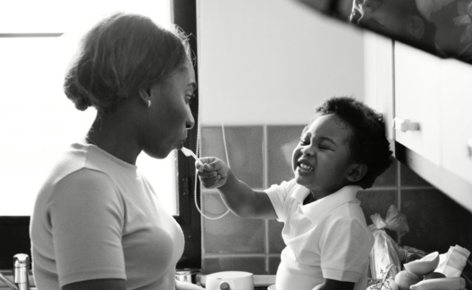 toddler feeds woman while sitting on countertop