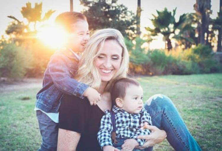 mother playing with her two kids in a park and sunshine